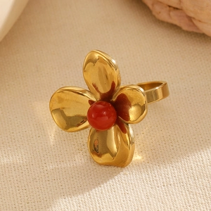 Detailed close-up of golden flower ring with red stone center and adjustable band