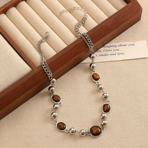 Detail der Perlenkette mit Tigerauge-Steinen und Silberperlen auf einer Holz-Displaybox