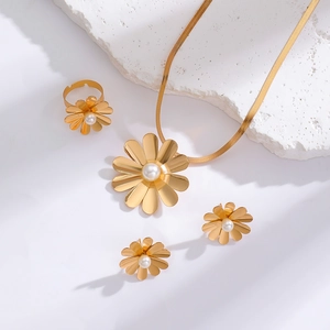Close-up of golden daisy jewelry set with white pearls on a white textured stone