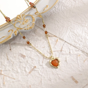 Makroaufnahme einer französischen Vintage-Goldkette mit einem bernsteinfarbenen Herz-Tigerauge