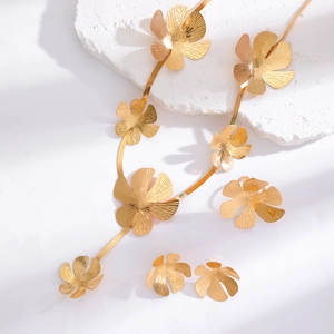 Detail of flower jewelry set with golden brushed metal petals on white stone pedestal