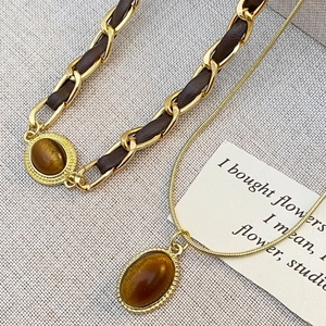 Details einer Vintage-Halskette mit Tigerauge-Anhänger und Leder-Gliederkette in Gold