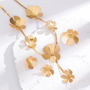 Detailed macro view of gold floral jewelry set with brushed matte texture on stone surface