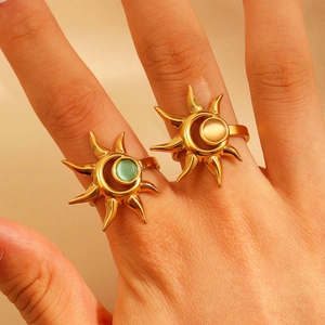 Close-up of 18k gold sunburst open rings featuring green and beige cat eye stone inlay