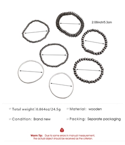 Macro shot of 6-piece dark grey wooden beaded bracelet set with engraved cylinder detail