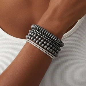Close-up of stacked grey matte beaded bracelets with sparkling zirconia accents on a model
