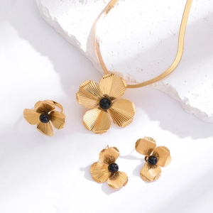 Detailed view of golden flower jewelry set with textured petals and black bead centers