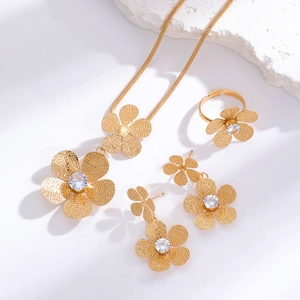 Macro detail of golden flower jewelry set with textured petals and zircon centerpieces