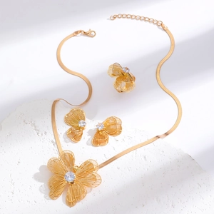 Detail of gold flower jewelry set with hollow petals and crystals on stone pedestal