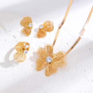 Detail of gold hollow flower jewelry set with sparkling zircon stones and flat snake chain