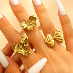 Detailed view of 18k gold heart and bow rings with textured finish on model's hand