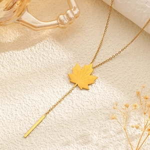 Close-up of 18k gold plated stainless steel necklace with maple leaf and tassel pendant