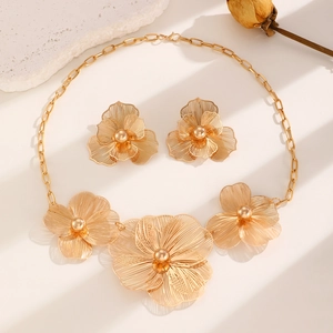 Detailed macro of hollow petal jewelry set with layered golden floral pendant and earrings