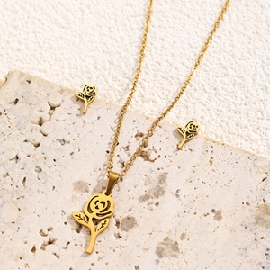 Macro detail of 18k gold plated flower necklace and earrings on stone tray