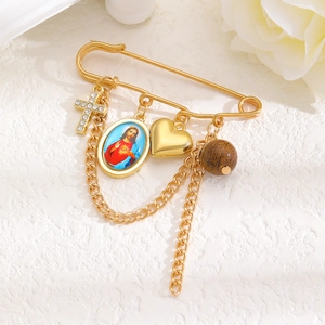 Détail de la broche religieuse vintage dorée avec croix en cristal et breloques cœur
