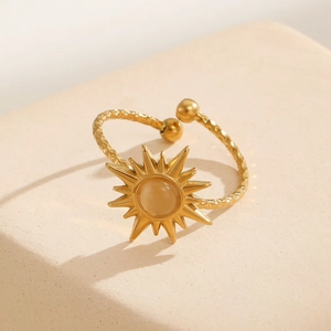 Detail of 18k gold plated sunburst ring with opal stone on a textured stone surface