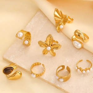 Detailed view of eight vintage gold rings with pearl and floral designs on marble background