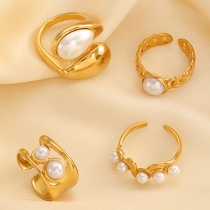 Detailed view of four golden pearl rings featuring chain and wavy designs on silk background