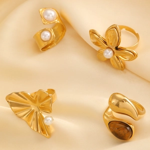 Detailed view of four 18k gold-plated rings with pearls and tiger eye on champagne silk