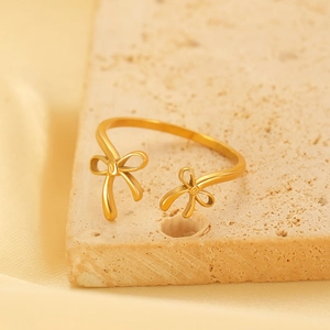 Detailed shot of gold bow open ring on stone surface with satin background