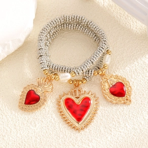 Nahaufnahme eines Retro-Perlenarmbandes mit goldenem Heiligem Herz und roten Emaille-Anhängern