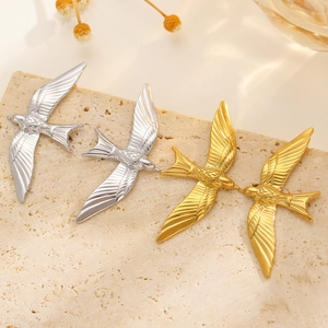Retro 18k gold and silver bird wing open rings with detailed feather textures on marble