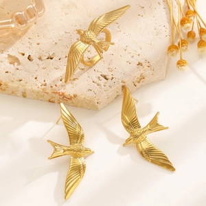 Detail of 18k gold plated stainless steel bird wings jewelry set with feather textures