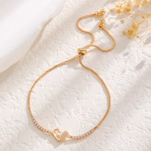 Detail of adjustable gold heart bracelet with sparkling zircon inlay and slider clasp