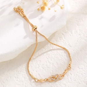 Detail of adjustable gold box chain bracelet featuring a diamond-set heart and infinity charm