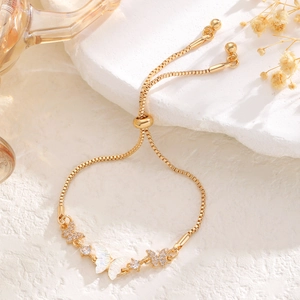 Macro detail of adjustable gold bracelet with shell butterfly and pavé butterfly charms