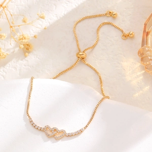 Detail of gold-plated double interlocking heart bracelet with adjustable slider clasp