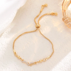Detailed macro view of adjustable golden box chain bracelet with pave set zircon V-pendant