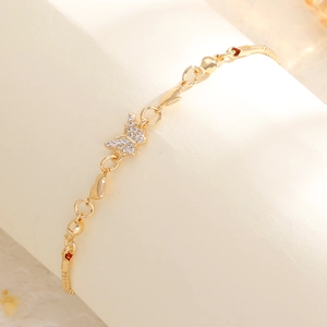 Macro detail of golden butterfly bracelet featuring sparkling pavé diamonds and heart charms