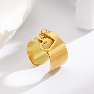 Macro dell'anello a fascia larga dorata con texture opaca e ciondolo a cuore