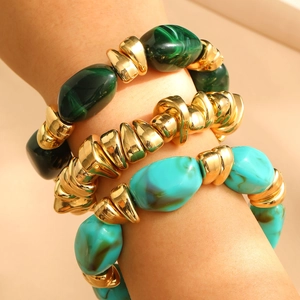 Close-up of stacked bohemian bracelets with turquoise resin beads and gold metal accents
