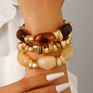 Detailed close-up of a three-piece chunky resin and gold metal bracelet set on a wrist