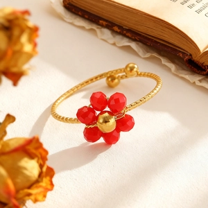 Detailansicht eines verstellbaren goldenen Blumenrings mit roten Perlen auf Vintage-Papier