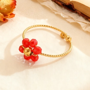 Detailaufnahme eines Vintage-Goldrings mit roten Kristallblüten auf einer Textur-Schiene