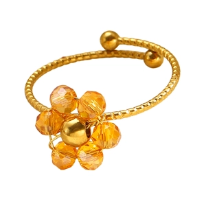 Makroaufnahme eines verstellbaren goldenen Rings mit orangefarbener Kristallblüte und Wellenband