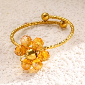 Detail eines Blumenrings mit orangen Kristallen und goldenem gewebtem Spiraldesign
