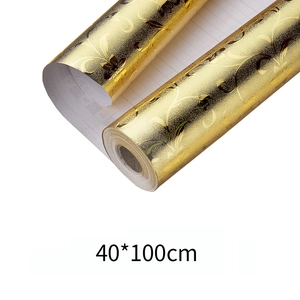 Macro shot of gold foil wall sticker roll with embossed floral patterns and grid lines