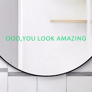 Modern black framed round mirror with You Look Amazing green glowing lettering on white tiles