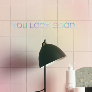 Holographic 'YOU LOOK GOOD' wall sticker with iridescent laser effect on pink tiles
