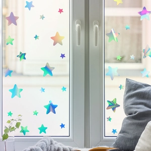 Detailed view of holographic star wall decals applied to a bright glass window at home