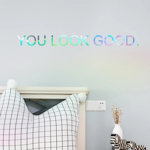 Close-up of holographic laser wall decal saying YOU LOOK GOOD in a modern bedroom setup