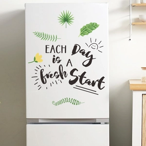 Close-up of 'Each Day is a Fresh Start' wall sticker with green plants on a white fridge