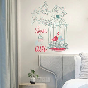Detail of birdcage and bird wall sticker with Love is in the air text on bedroom wall