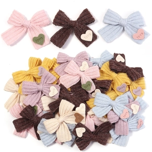 Detailansicht bunter gestrickter Schleifen mit gravierten Love-Herz-Anhängern