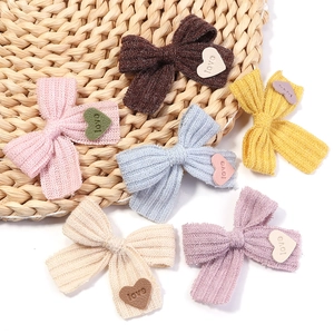 Nahaufnahme bunter Strickschleifen mit geprägten Herz-Lederetiketten und Love-Schriftzug