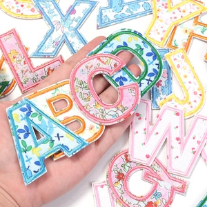 Close-up of floral alphabet embroidery patches with colorful patterns and stitched edges